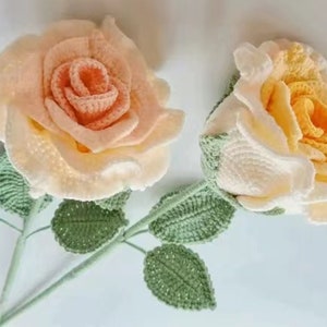 May include: Two crocheted roses with green leaves. One rose is peach and the other is yellow.
