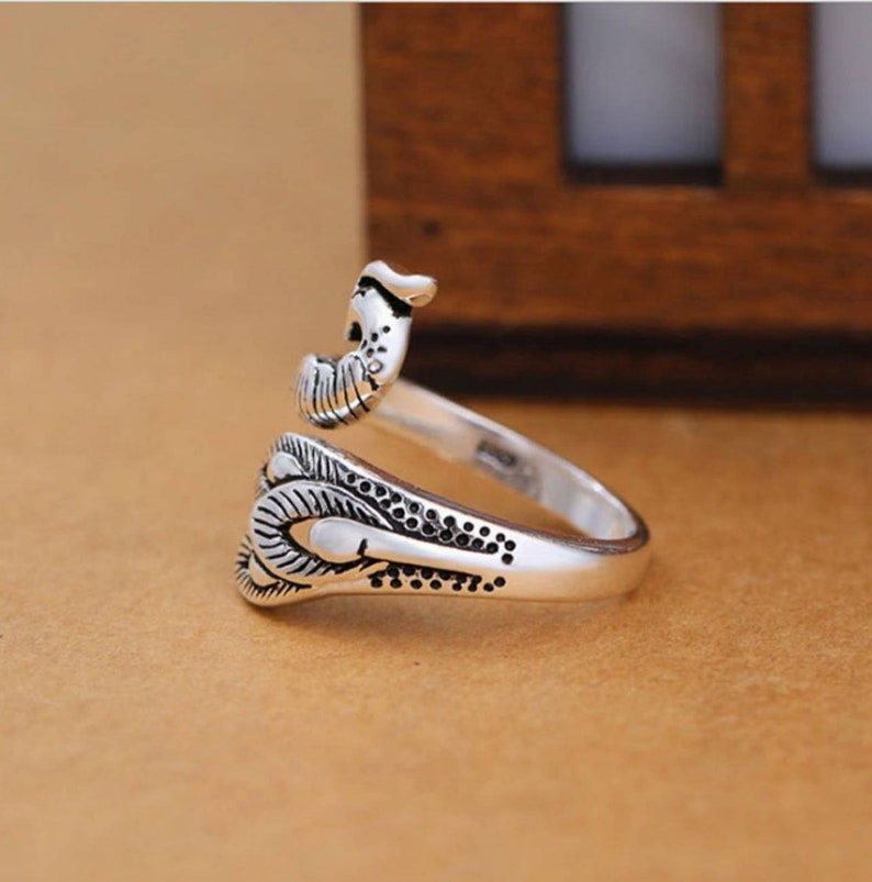 Peut inclure: Une bague en argent avec un motif d&eacute;taill&eacute; d'un oiseau aux ailes d&eacute;ploy&eacute;es. La bague est ouverte et r&eacute;glable.