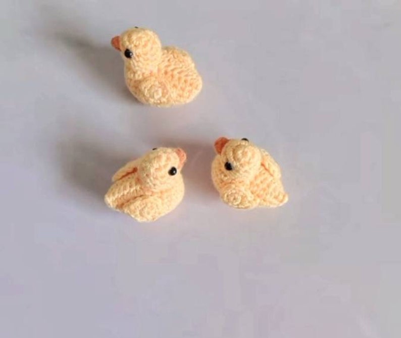 Puede incluir: Tres peque&ntilde;os patitos amarillos de crochet con ojos negros.
