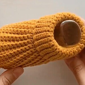 May include: A yellow crocheted slipper with a round opening at the top.