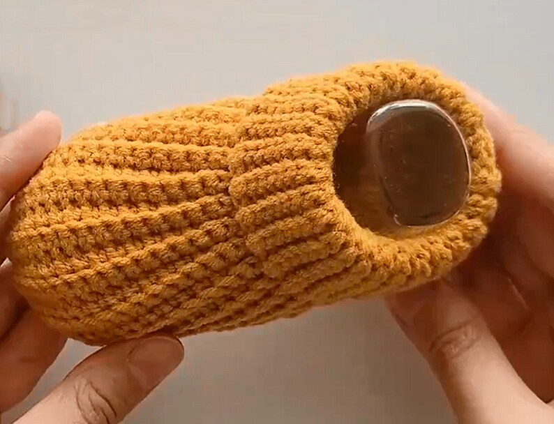 May include: A yellow crocheted slipper with a round opening at the top.