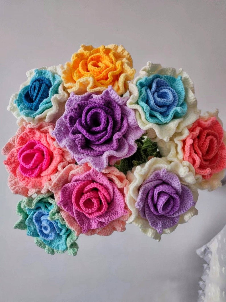 May include: A bouquet of crocheted roses in a rainbow of colours, including pink, purple, blue, yellow, and white.