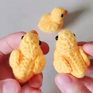 Puede incluir: Tres pollitos amarillos tejidos a crochet con ojos negros. Los pollitos son peque&ntilde;os y tienen una textura esponjosa.