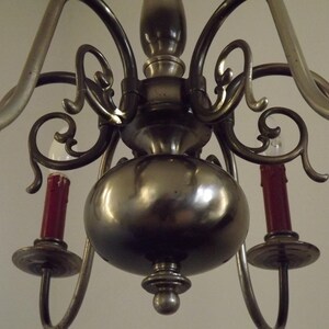 Peut inclure: Un lustre ancien en laiton avec de multiples bras incurv&eacute;s et des volutes d&eacute;coratives. Le lustre comporte des ampoules rouges en forme de bougie et un corps central arrondi. Un luminaire classique.