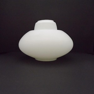 Op de afbeelding: Een witte matglazen lampenkap met een afgerond, bolvormig lichaam en een kleinere, cilindrische hals aan de bovenkant. Het glas heeft een gladde, matte afwerking die het licht verspreidt, met een breed, gebogen middengedeelte naar de opening.