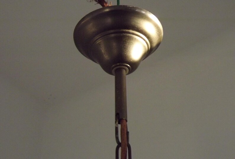 Peut inclure: Gros plan d'une rosace de plafond de couleur bronze avec une tige centrale et une cha&icirc;ne. La rosace a une forme arrondie en forme de cloche et une finition m&eacute;tallique chaude. La cha&icirc;ne est de couleur marron fonc&eacute;.