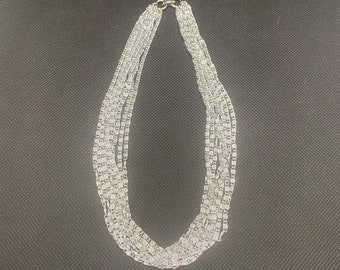 May include: A silver chain necklace with multiple strands. The necklace is made of a delicate, linked chain.