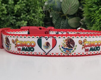 May include: A red and white dog collar featuring a Cinco de Mayo design. The collar has a red buckle and is decorated with the Mexican flag, maracas, and the words "Cinco de Mayo".
