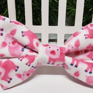This adorable Pig Bow Tie has a White background with cute Pink Pigs. It is made with Cotton Fabric and Interfacing with either 2 hook and loop attachments, or an adjustable elastic strap.