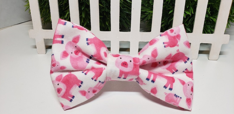 This adorable Pig Bow Tie has a White background with cute Pink Pigs. It is made with Cotton Fabric and Interfacing with either 2 hook and loop attachments, or an adjustable elastic strap.