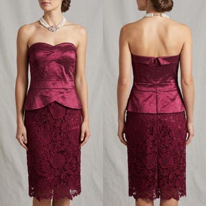 May include: A burgundy strapless dress with a textured bodice and a lace skirt. The bodice has a crisscross design and a peplum waist. The skirt is knee-length and features a floral lace pattern. The dress is shown from the front and back.
