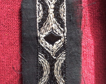bande de coton noir de 4cm brodé de fils de soie blancs et gris la broderie mesure 2cm de large galon vendu au mètre.