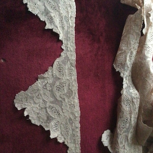 Peut inclure: Deux morceaux de dentelle blanche à motifs floraux. La dentelle est sur un fond bordeaux.