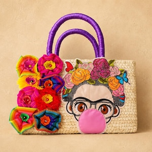 May include: A straw handbag featuring two purple wrapped handles and a colorful floral arrangement on the left side. The front displays an embroidered portrait of a person with a floral crown, glasses, and a large pink bubble gum bubble.