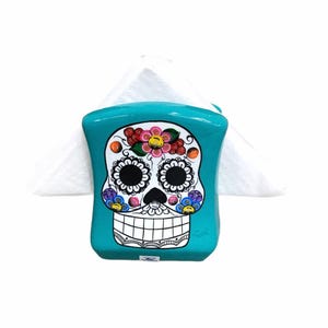 Serviettenspender, Serviettenhalter aus Ton mit Bild von la catrina oder geflochtener Totenkopf mit Zöpfen auf der einen Seite und dekorativen Blumen auf der anderen.