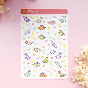 May include: A sheet of colorful dinosaur stickers with a white background. The stickers feature various dinosaurs in different colors and poses. The sheet is titled "Cute Dinosaurs" and includes the website address @dinomandk.com.