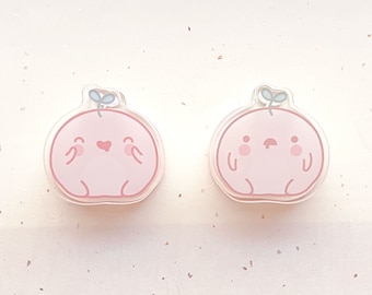 May include: Two pink cartoon character charms with a green leaf on top. One charm has a heart and a smile, the other has a frown and two dots for eyes.