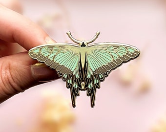 May include: Gold-tone metal butterfly pin with a green and brown enamel design. The butterfly has intricate details and a delicate appearance.