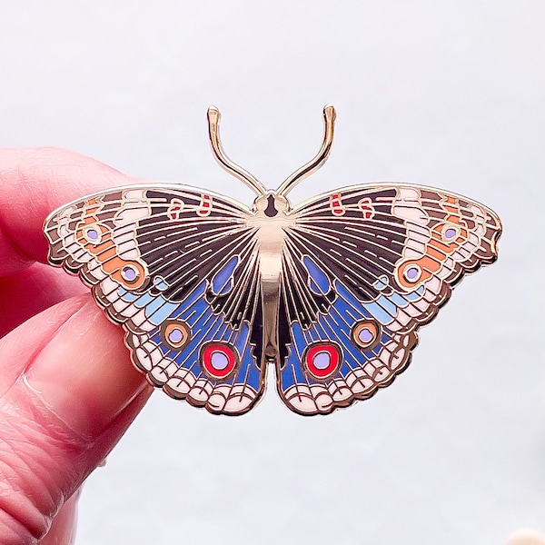 Pin esmaltado de mariposa con pensamiento azul