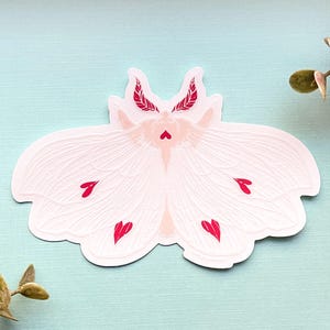 May include: White moth sticker with red heart accents. The moth has feathery antennae and wings with a delicate, textured design.