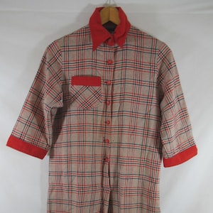 May include: A vintage one-piece plaid garment with a red collar, pocket, and sleeve cuffs. The plaid pattern features tan, red, and navy blue lines. The garment has a button-up front and three-quarter sleeves.