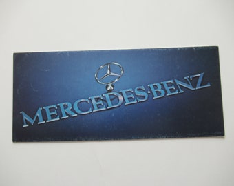 May include: A blue and silver Mercedes-Benz logo on a dark blue background.