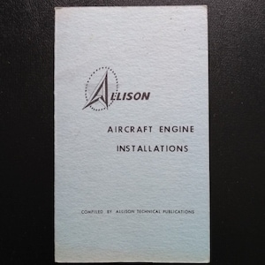 May include: A white booklet with a black and white logo of a stylized letter A with a circle of stars around it. The text "Allison" is below the logo. The text "Aircraft Engine Installations" is below the logo. The text "Compiled by Allison Technical Publications" is at the bottom of the booklet.
