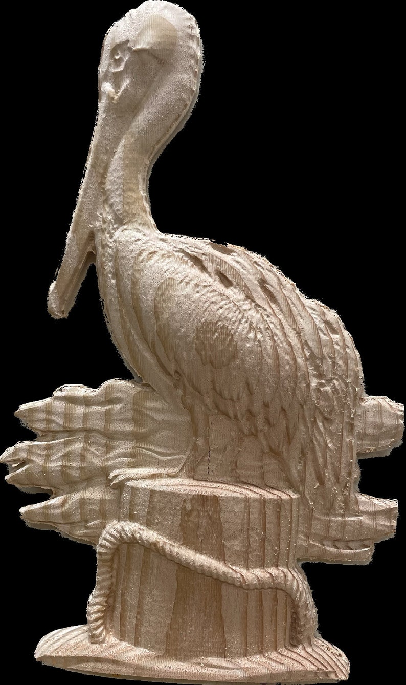 May include: A carved wooden pelican sculpture. The pelican is perched on a wooden piling with a rope wrapped around it. The sculpture is made of light-colored wood and has detailed carvings of the bird's feathers and features.