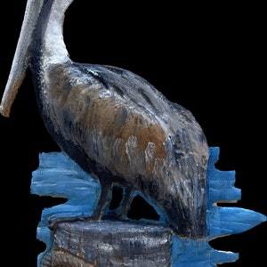 May include: A painted wooden sculpture of a pelican perched on a weathered wooden piling. The pelican has a yellow head, a long gray beak, and brown and gray feathers. The piling is wrapped with a rope and sits in front of a blue water background.
