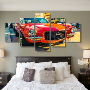 May include: A five-panel wall art print featuring a classic red sports car. The car is a vintage model with chrome accents and the letters "SS" on the front grill. The artwork is displayed above a bed with white bedding and decorative pillows.