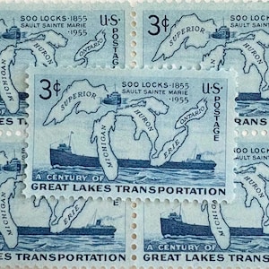 May include: A sheet of U.S. postage stamps featuring a blue and white illustration of the Great Lakes and a ship. The stamps commemorate the "Century of Great Lakes Transportation" and the Soo Locks.