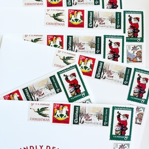 Pode incluir: Um envelope branco com a inscri&ccedil;&atilde;o vermelha "KINDLY DELIVER TO" e a inscri&ccedil;&atilde;o vermelha "The Weaver Family". O envelope &eacute; decorado com v&aacute;rios selos de Natal vintage que mostram imagens do Papai Noel, um cavalo de balan&ccedil;o, um anjo e uma cena de inverno. Os selos s&atilde;o do Servi&ccedil;o Postal dos Estados Unidos e mostram o texto "Christmas" e "U.S. Postage".