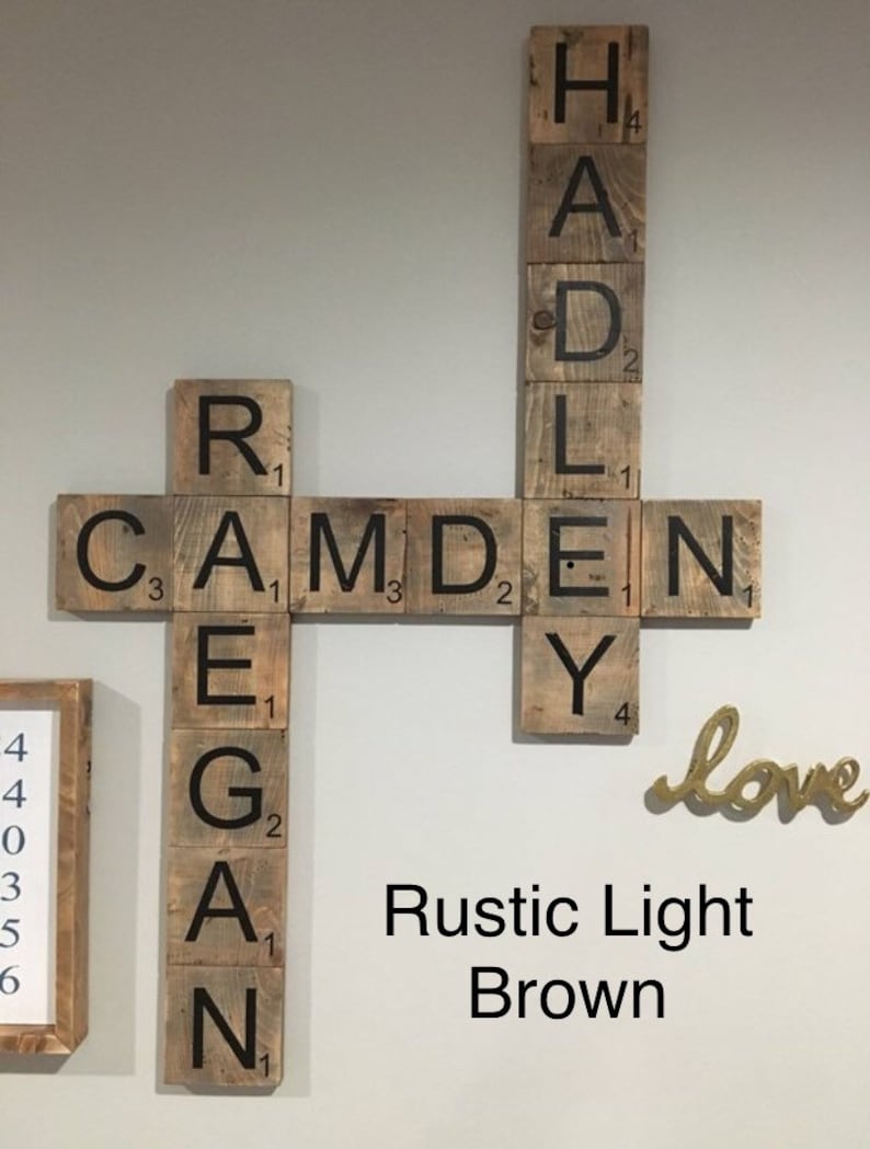 Puede incluir: Azulejos de Scrabble de madera marr&oacute;n claro r&uacute;stico que deletrean los nombres "Camden" y "Hadley" con la palabra "love" en letras doradas debajo.