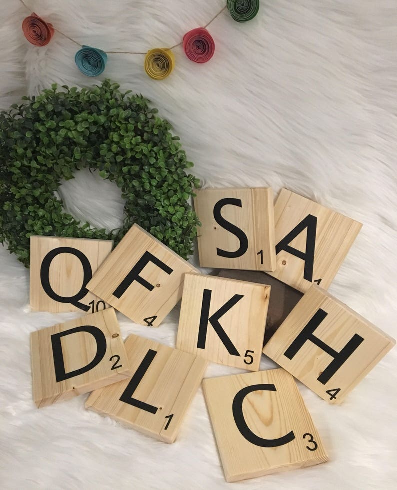 Puede incluir: Azulejos de Scrabble de madera que deletrean el nombre "SAKHL" en letras negras sobre un fondo blanco. Los azulejos est&aacute;n dispuestos en semic&iacute;rculo con la "S" en la parte superior y la "L" en la parte inferior.