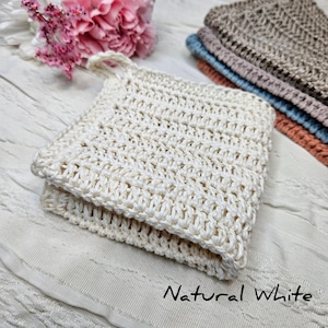 May include: A natural white crocheted washcloth with a textured pattern. The washcloth is folded in half and has a loop for hanging.