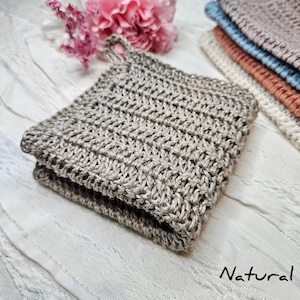 May include: A natural brown knitted dishcloth with a loop handle. The dishcloth is folded in half and lying on a white surface. The word "Natural" is written in cursive below the dishcloth.