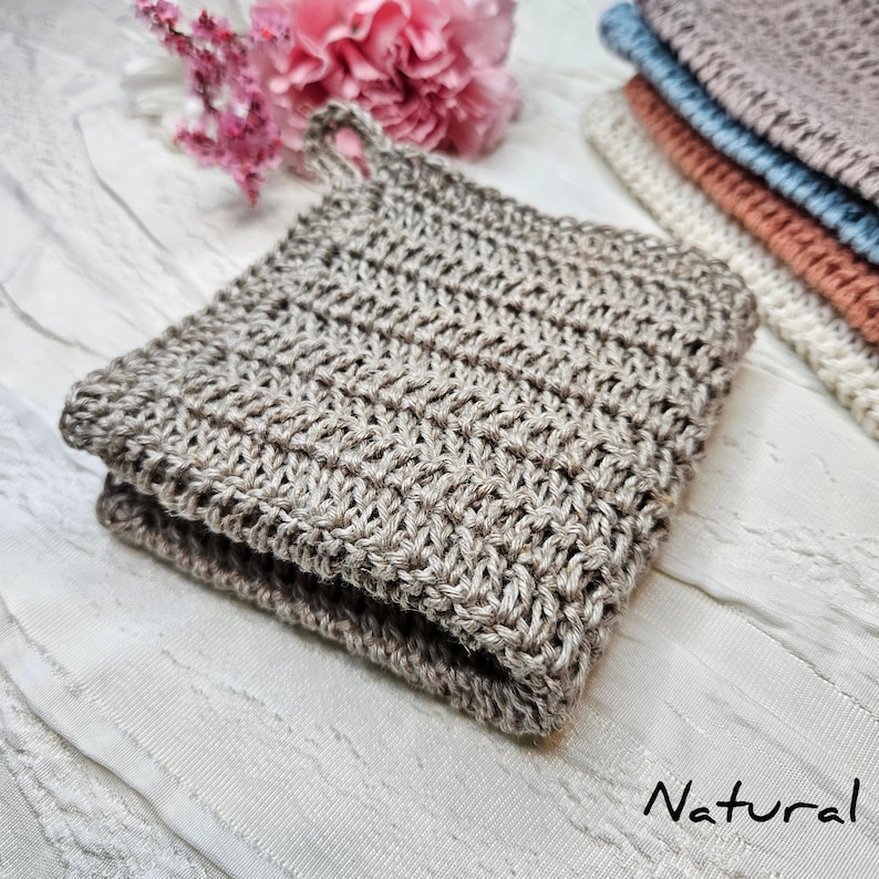 May include: A natural brown knitted dishcloth with a loop handle. The dishcloth is folded in half and lying on a white surface. The word "Natural" is written in cursive below the dishcloth.