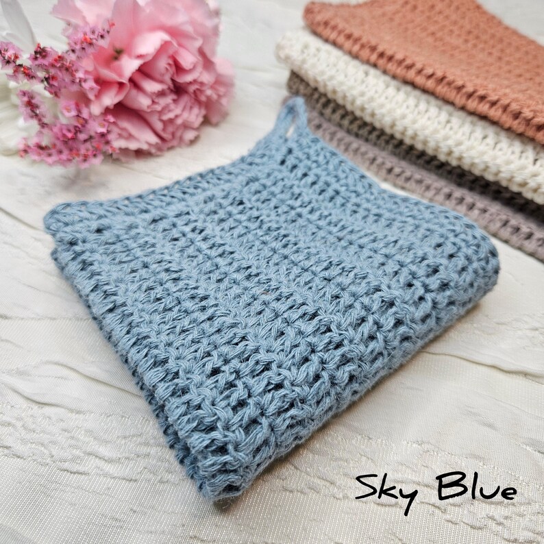 May include: A sky blue crocheted dishcloth or kitchen towel. The cloth is made with a textured stitch pattern.