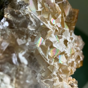 May include: A cluster of iridescent, light brown fluorite crystals with a white, crystalline matrix. The crystals have a sharp, geometric shape and a glassy luster.