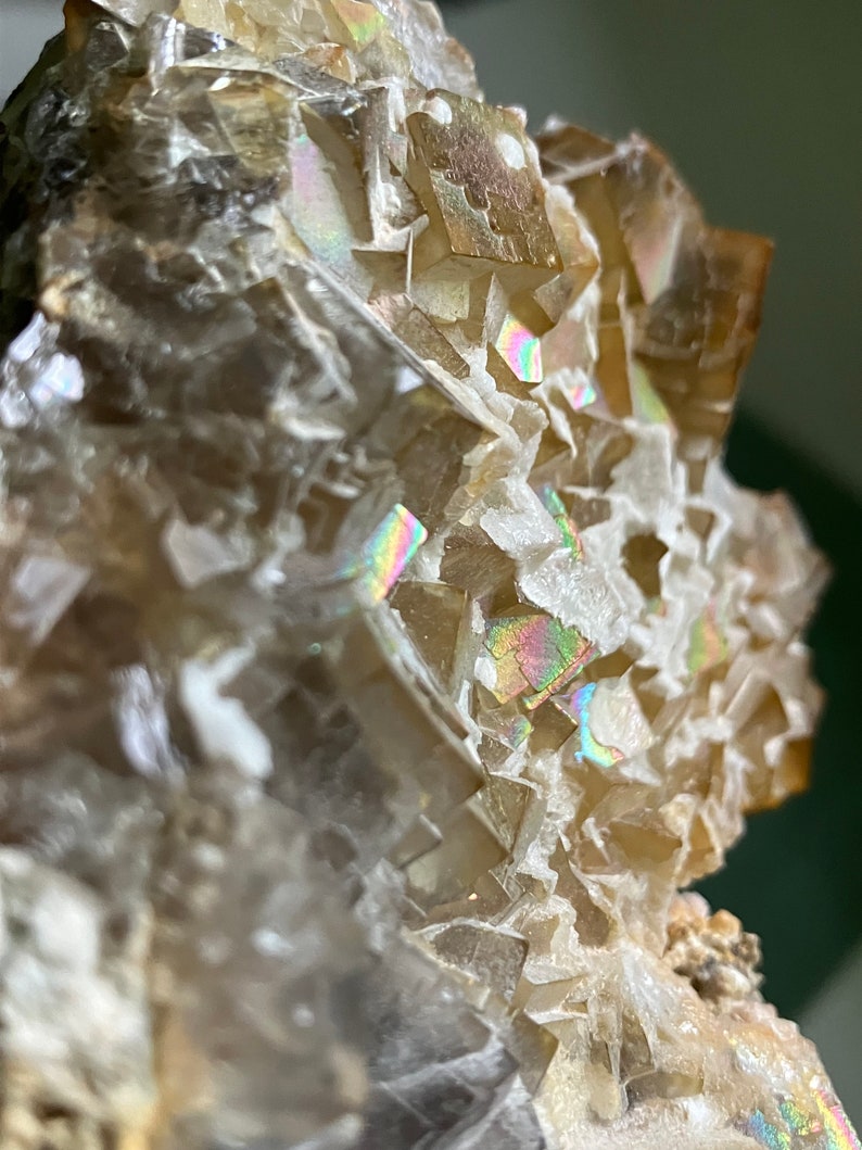 May include: A cluster of iridescent, light brown fluorite crystals with a white, crystalline matrix. The crystals have a sharp, geometric shape and a glassy luster.