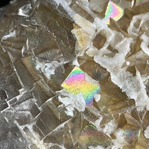 May include: Close-up of a brown and clear crystal with iridescent rainbow colors. The crystal has a rough, textured surface.
