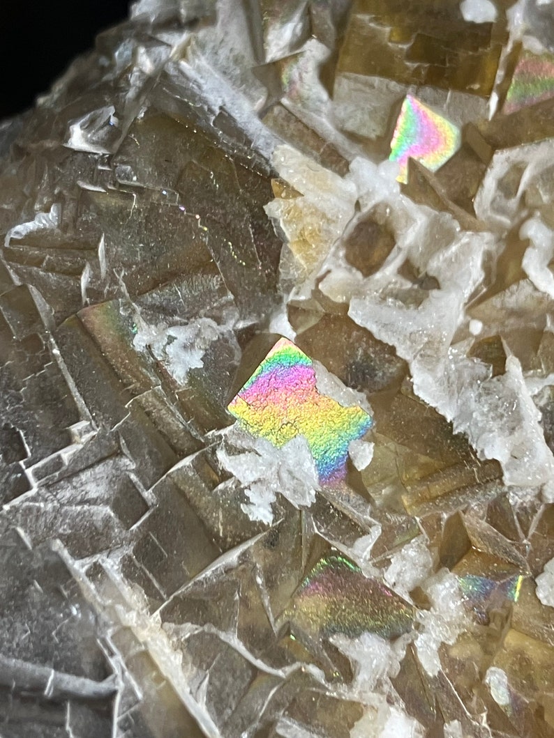 May include: Close-up of a brown and clear crystal with iridescent rainbow colors. The crystal has a rough, textured surface.