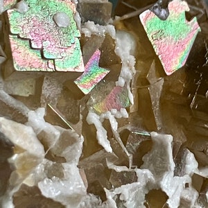 May include: Close-up of a cluster of iridescent brown fluorite crystals with a white mineral matrix. The crystals have a variety of shapes and sizes, and some have a rainbow-like sheen.