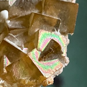 May include: A cluster of iridescent brown calcite crystals with a light brown color and a white base.
