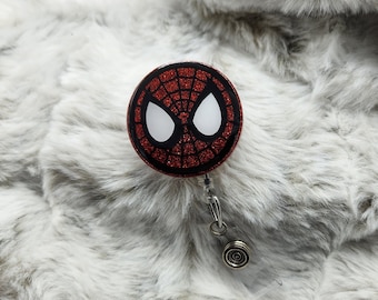 May include: Red and black glitter badge reel with a white Spider-Man mask design.