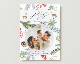 Puede incluir: Tarjeta de Navidad con una foto familiar dentro de un marco circular. La tarjeta presenta ilustraciones en acuarela de ciervos, ramas de pino y bayas. El texto incluye "joy to the world", "with love" y "The Brown Family", con el año 2024.