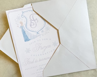Puede incluir: Un sobre blanco con una invitación doblada en su interior. La invitación presenta una ilustración de acuarela de Elsa de Frozen, copos de nieve y el texto "Join us for a Frozen Celebration Ford is turning... Saturday, February... 123 Cinna Jack"