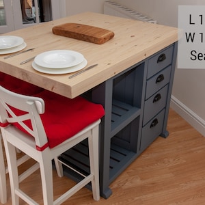 May include: A wooden kitchen island with a light wood countertop, four white bar stools with red cushions, and a grey base with drawers and shelves. The island is 130cm long and 100cm wide and seats four people.