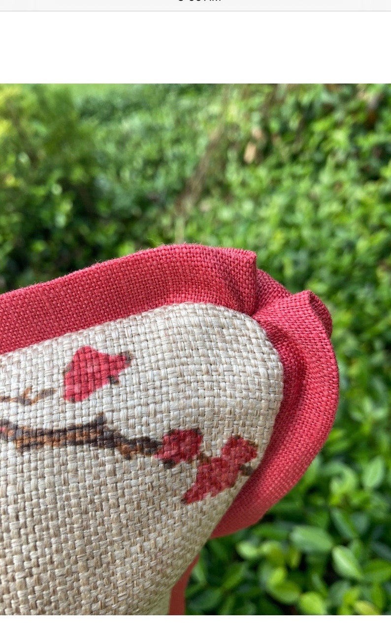 Pode incluir: Close-up de um travesseiro vermelho e bege com um padr&atilde;o floral. O travesseiro tem uma borda vermelha e uma textura tecida.