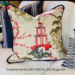 Pode incluir: Uma almofada branca com uma guarni&ccedil;&atilde;o azul marinho de franja apresenta um design asi&aacute;tico colorido com uma pagoda vermelha, flores de cerejeira e &aacute;rvores.